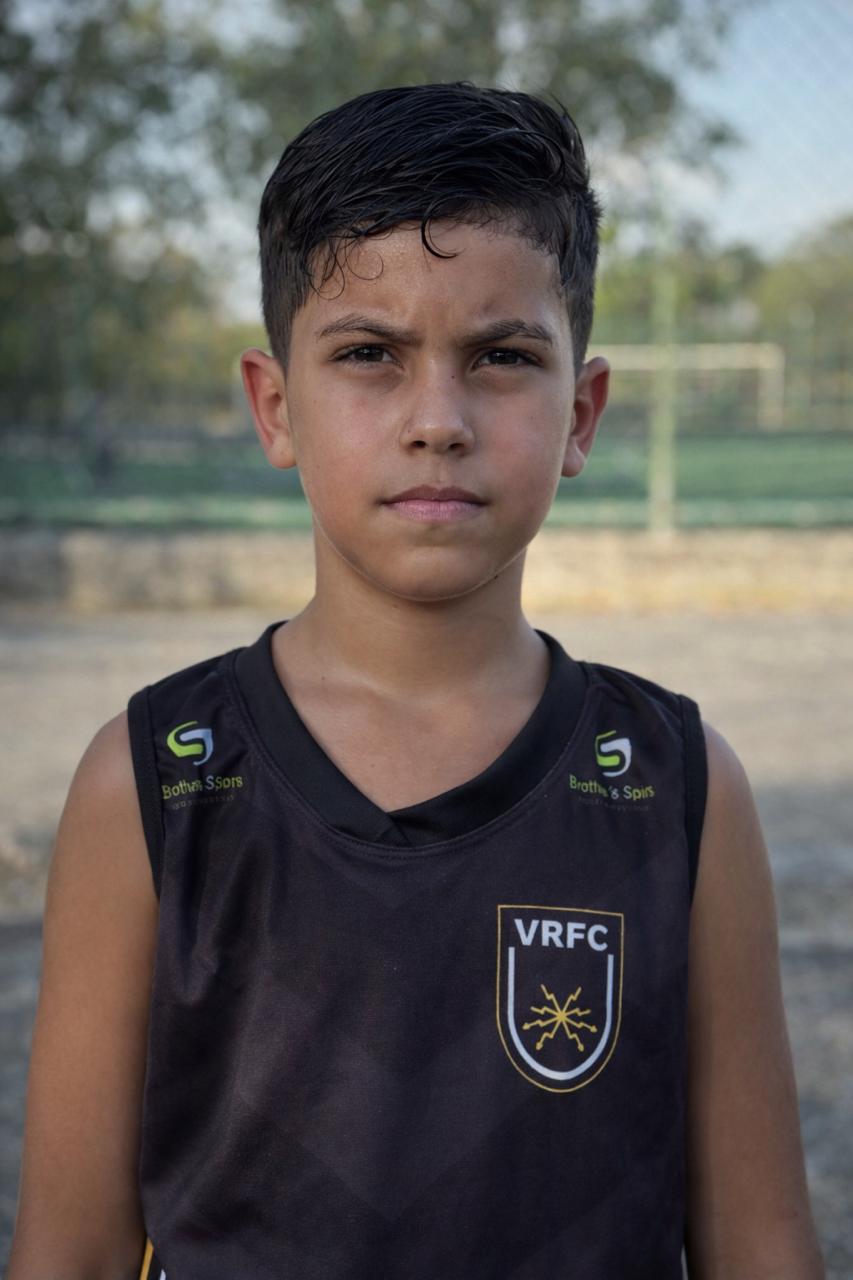 Hugo de colete preto do VRFC, olhando para a câmera ao lado do campo